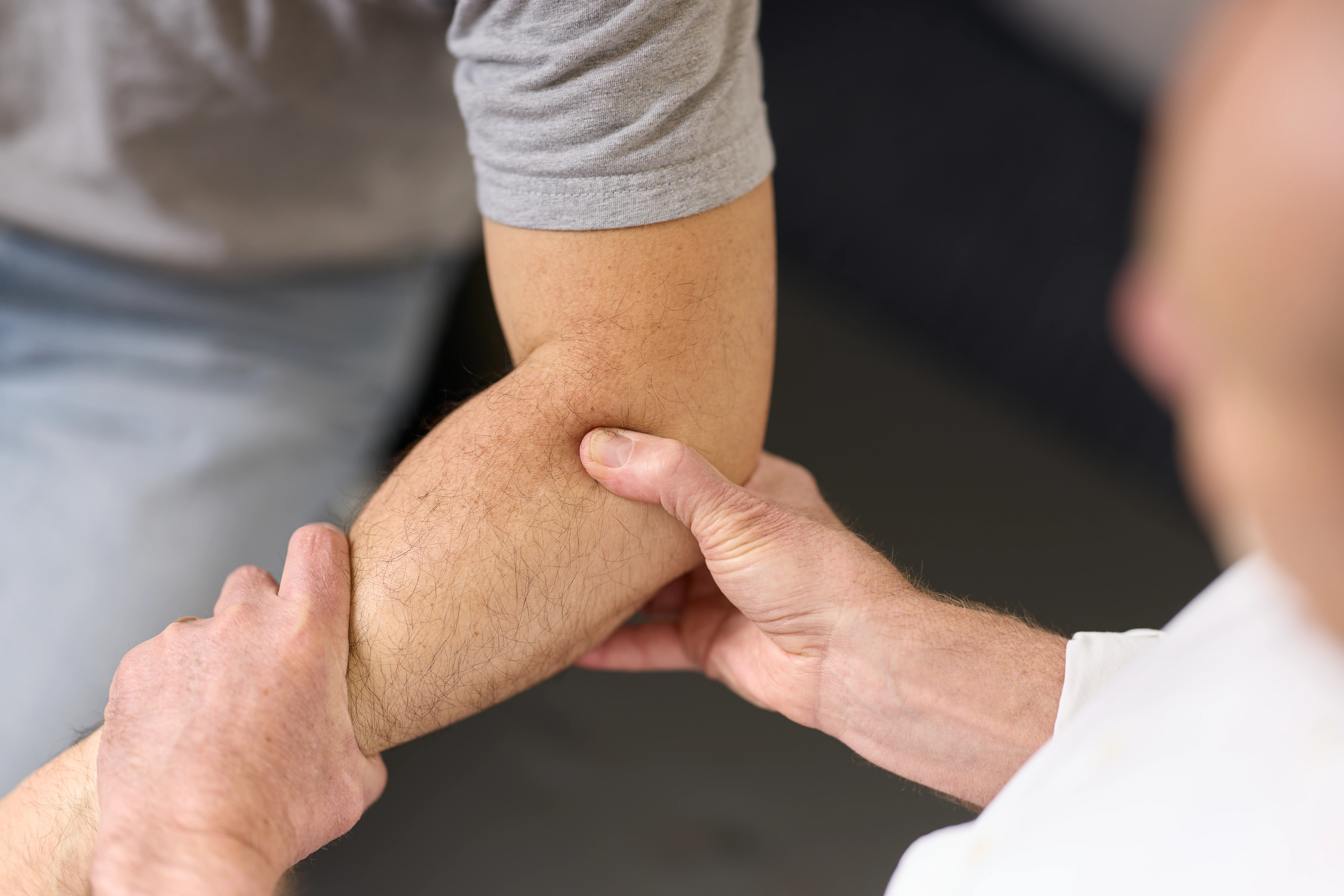 Dr Ken Leembruggen, chiropractor, giving male patient treatment on his elbow at Chiropractic Solutions Norwood Adelaide