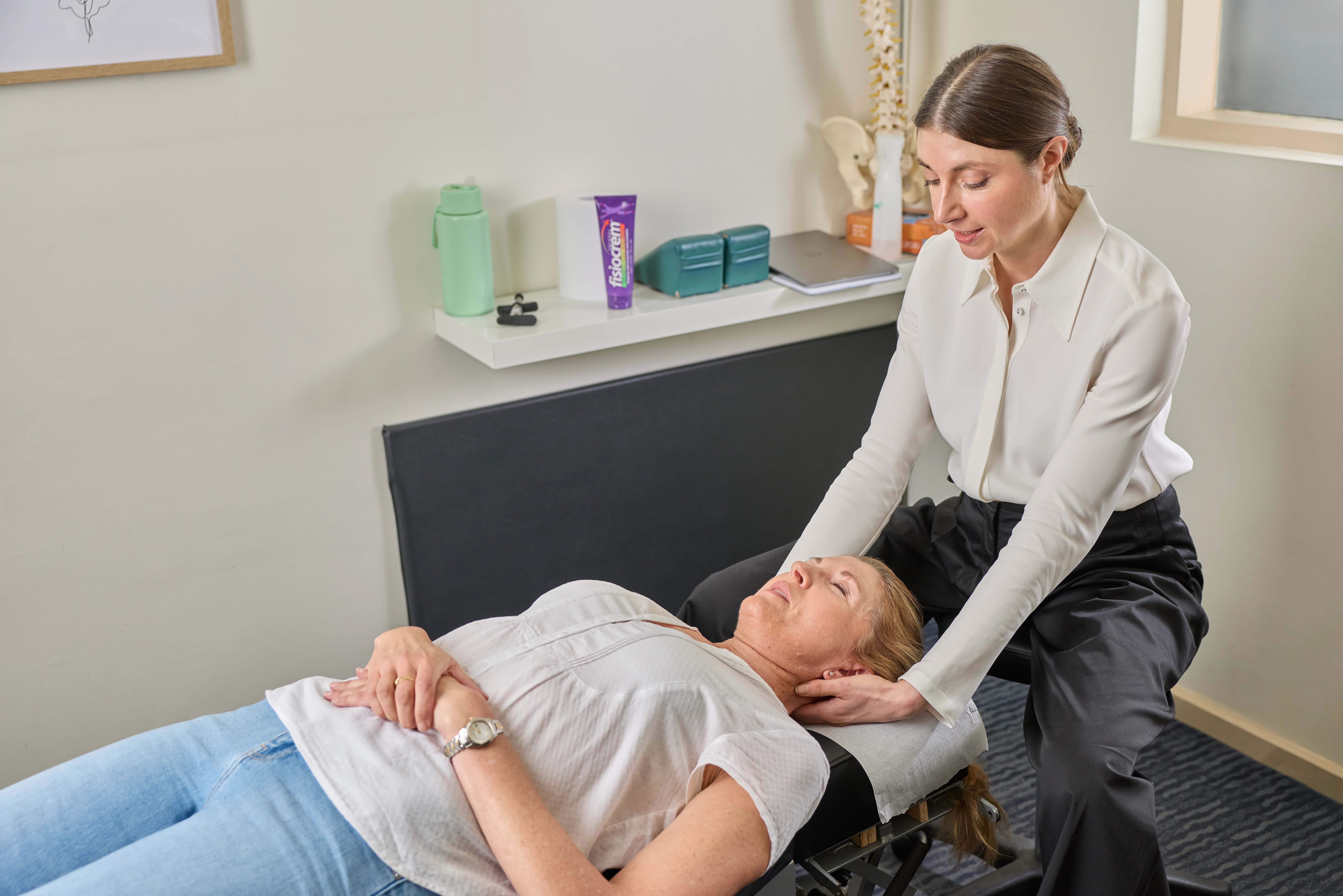 Dr Kimberley Manz, chiropractor, giving a female patient lying on her back a neck adjustment at Chiropractic Solutions Norwood Adelaide