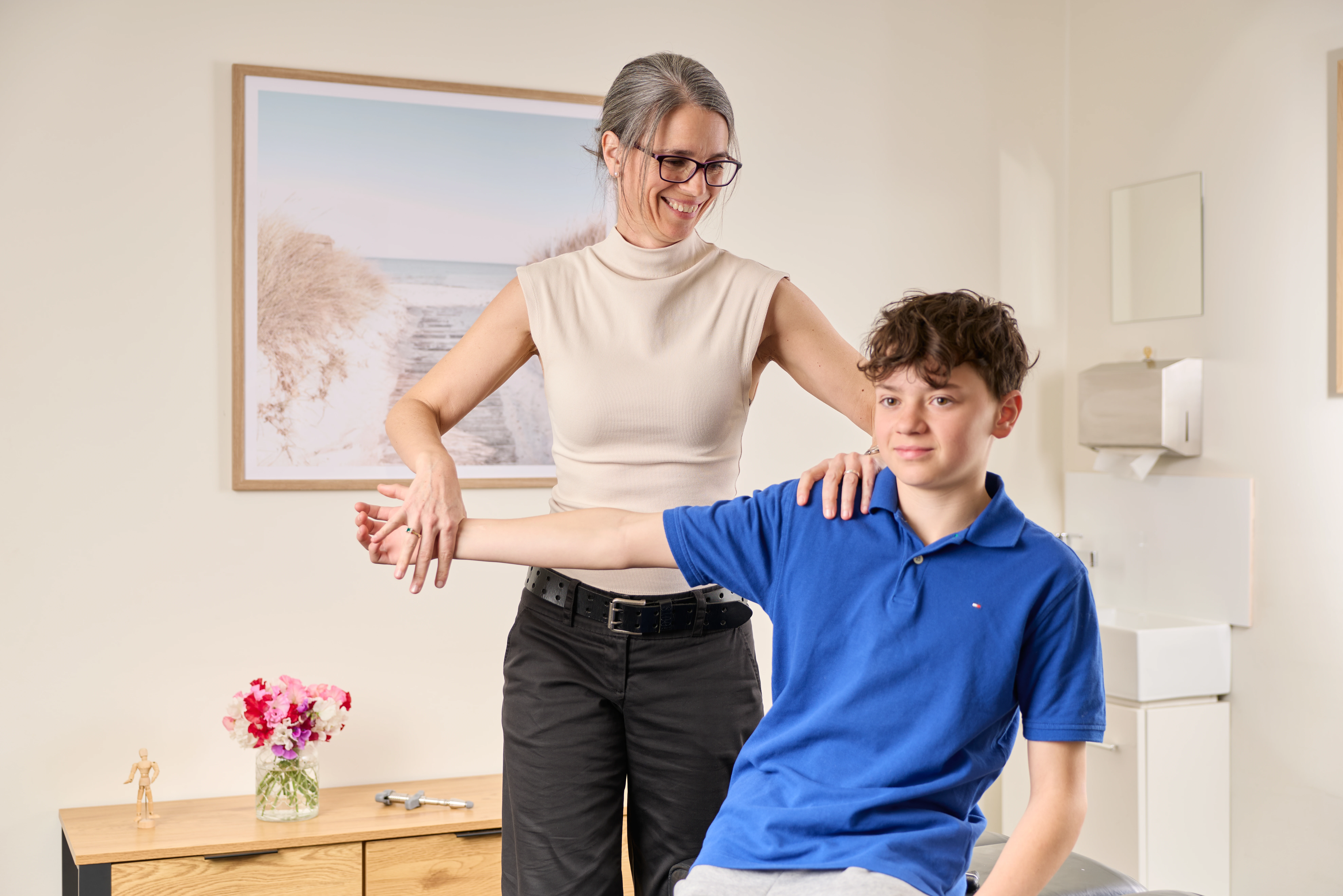 Dr Adrienne Wilson, chiropractor performing a muscle test on a teenage boy at Chiropractic Solutions Norwood Adelaide